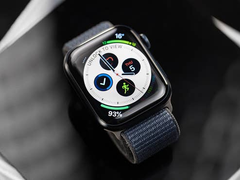 Nahaufnahme der Apple Watch Series 9 mit dunklem Textilarmband und Infograph-Zifferblatt, Batteriestand bei 93 %.