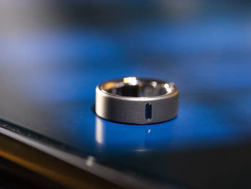 Eine Nahaufnahme des Oura Ring 4, der auf einer reflektierenden Oberfläche liegt.