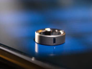 inside-digital-oura-ring-mark Eine Nahaufnahme des Oura Ring 4, der auf einer reflektierenden Oberfläche liegt.