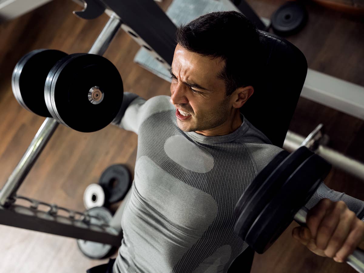 Starker Mann stemmt enormes Gewicht beim Bankdrücken im Fitnessstudio