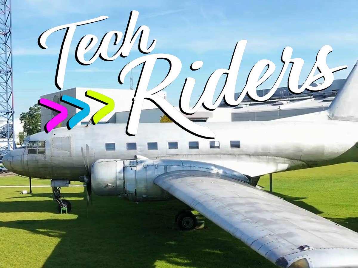 Ein Vintage-Flugzeug auf grünem Gras mit dem Text 'Tech Riders.