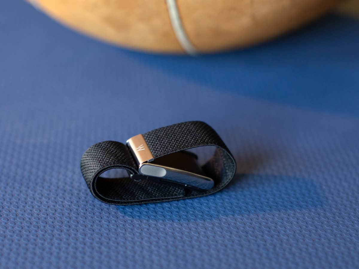 Ein Whoop MG Sensorarmband liegt auf einer blauen Oberfläche, mit einem Basketball, der teilweise im Hintergrund sichtbar ist.