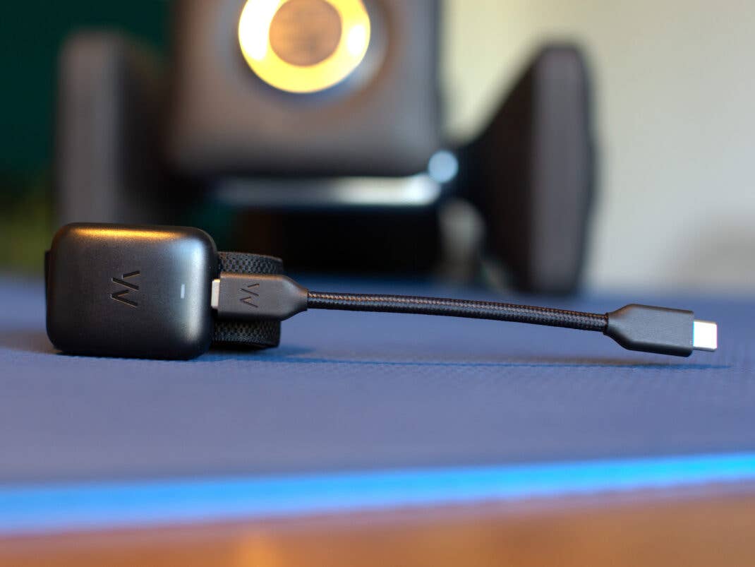 Ein Whoop MG-Sensor, verbunden mit einem schwarzen USB-Kabel, auf einer blauen Matte platziert.