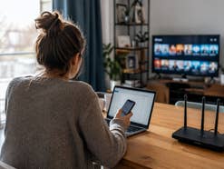 Eine Frau sitzt vor einem Laptop am Tisch.
