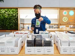 Verkäuferin mit iPhone 12 im Apple Store