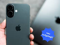 Im Vordergrund hält eine Hand ein iPhone 17 mit der Rückseite in die Kamera, im Hintergrund liegt ein MacBook