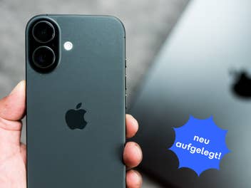 Im Vordergrund hält eine Hand ein iPhone 17 mit der Rückseite in die Kamera, im Hintergrund liegt ein MacBook