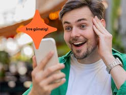 Mann schaut erfreut auf sein Smartphone