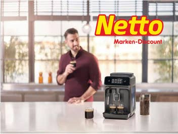 Ein Mann steht mit einem Kaffee in der Küche. Davor ist ein Philips Kaffeevollautomat und ein netto Logo zu sehen.
