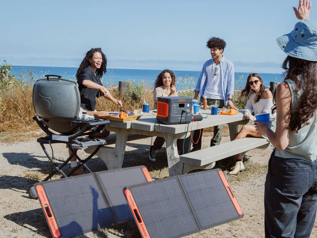 Die Jackery Explorer 2000 v2 wird über SolarSaga 200-Solarpaneele aufgeladen während einer Strandparty.