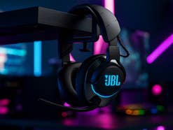 Das JBL Quantum 810 Gaming-Headset hängt an einem Schreibtisch in einem dunklen Gaming-Raum.