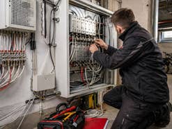 Ein Techniker arbeitet an einem Verteilerkasten im Keller eines Hauses