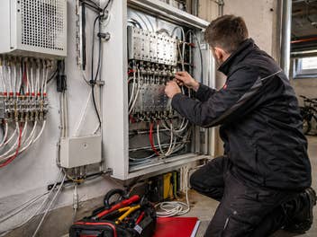 Ein Techniker arbeitet an einem Verteilerkasten im Keller eines Hauses