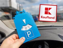 Ein Autofahrer hält eine Parkscheibe in der Hand, im Hintergrund ist ein Parkplatz und das Kaufland-Logo zu sehen
