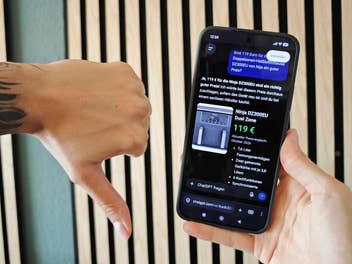 Hand hält Handy, andere zeigt Daumen nach unten