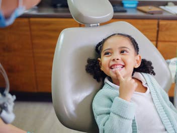 Kind beim Zahnarzt zeigt auf seine Zähne.