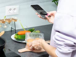 Eine Frau kocht und hält ihr Handy in der Hand