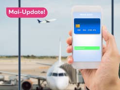 Eine auf einem Handy gespeicherte Kreditkarte vor einer Flughafen-Situation