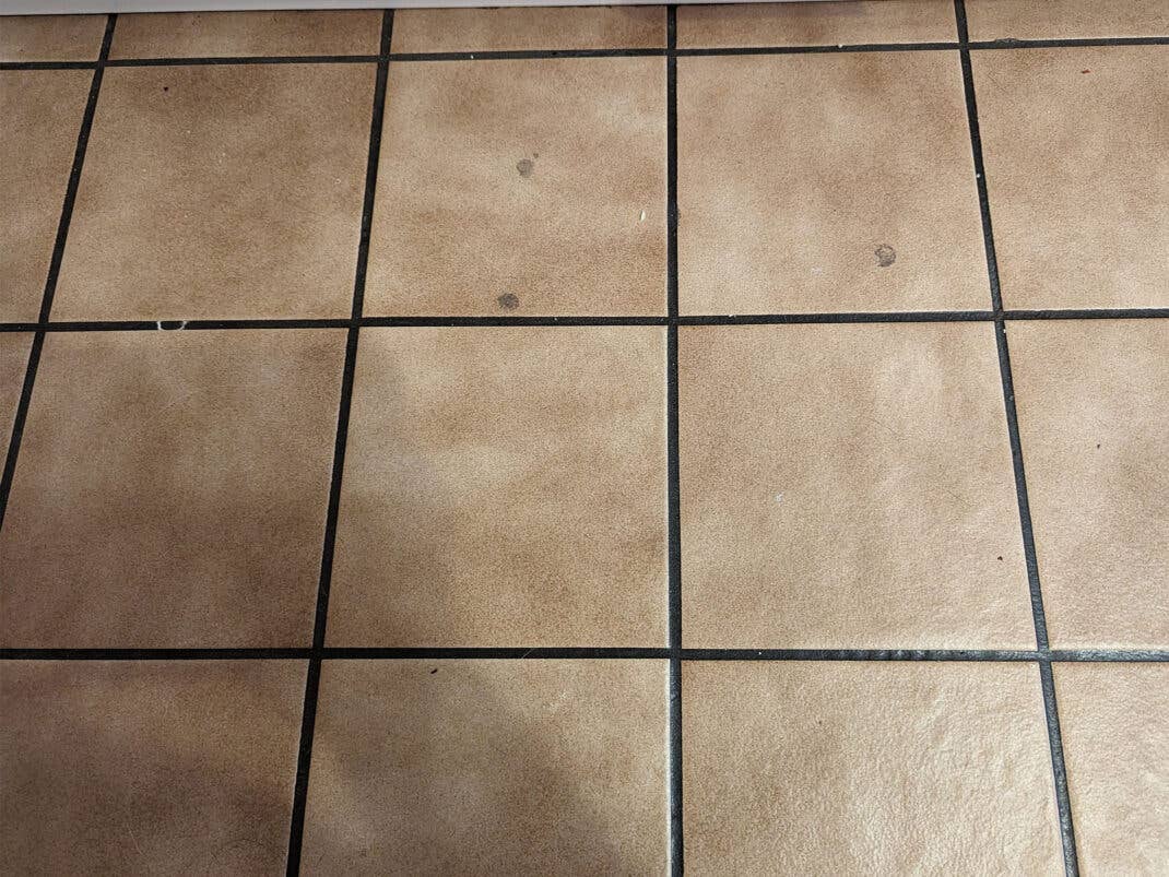 Krümmel und Flecken auf einem Küchenboden vor der Reinigung