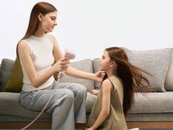 Frau föhnt einem Kind die Haare