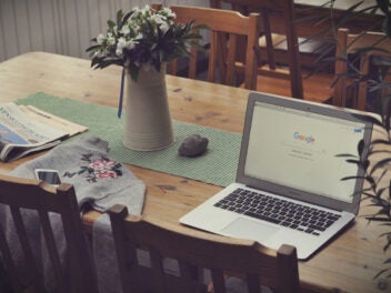 Ein Laptop auf einem Holztisch. auf dem Google geöffnet ist.