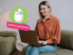 Frau sitzt auf einem Sofa und arbeitet mit dem Laptop
