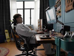 Ein Mann sitzt auf einem LiberNovo Bürostuhl in einem Büro und arbeitet