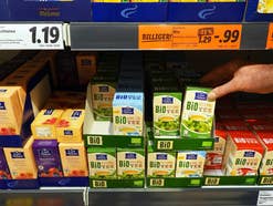 Eine Person greift nach einem Produkt im Lidl-Regal.