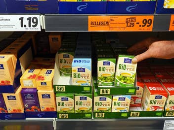 Eine Person greift nach einem Produkt im Lidl-Regal.