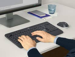 Eine Person sitzt am Schreibtisch und tippt auf einer Tastatur