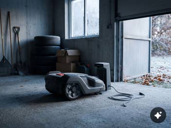 Mähroboter im Winter einlagern Ein Rasenmäherroboter in einem offenen Gartenhaus