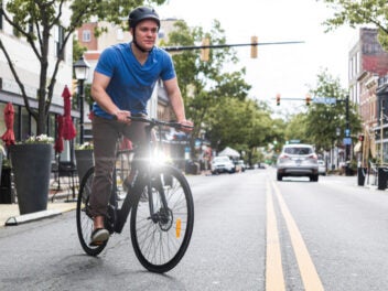 Ein Mann mit Helm fährt E-Bike auf einer Straße.