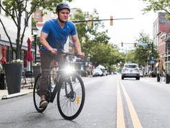 Ein Mann mit Helm fährt E-Bike auf einer Straße.
