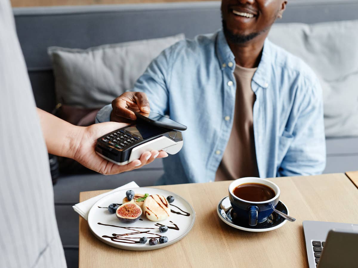 Ein Mann bezahlt im Café per Apple Pay Ein Mann bezahlt im Café per Apple Pay