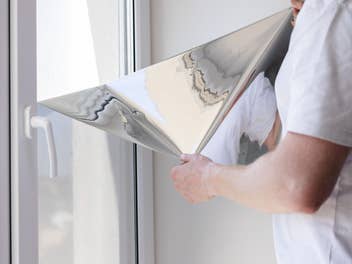 Mann bringt UV-Sonnenschutzfolie am Fenster an