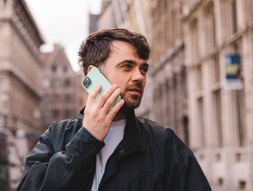Mann hält ein Smartphone und telefoniert Mann hält ein Smartphone und telefoniert