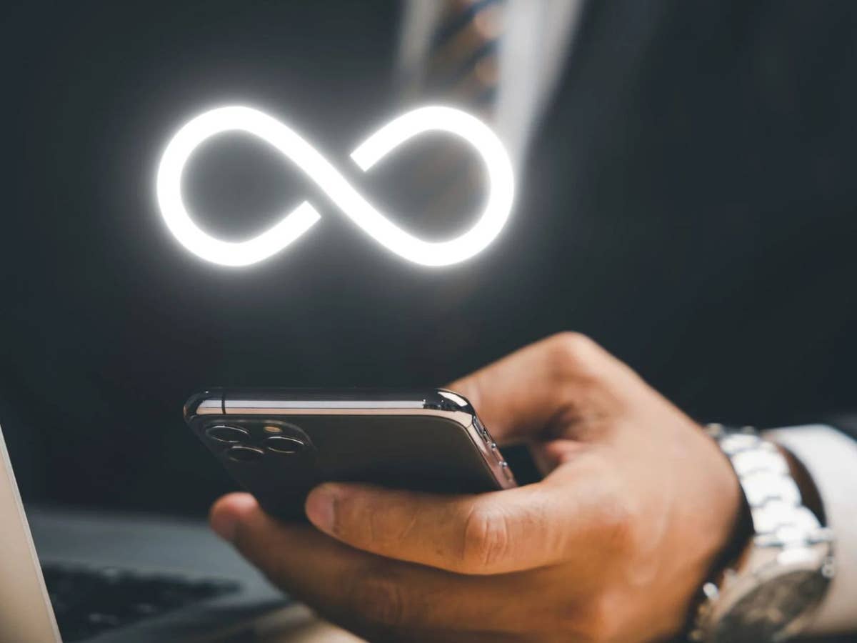 Darum lohnt sich ein Unlimited-Handytarif jetzt für fast jeden Mann hält Smartphone in der Hand, darüber das Unendlichkeitszeichen