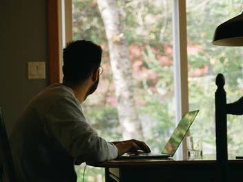 Ein Mann sitzt an einem Tisch vor seinem Laptop