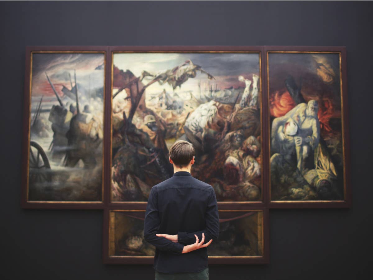Ein Mann steht vor einem großen Gemälde mit dem Rücken zur Kamera.