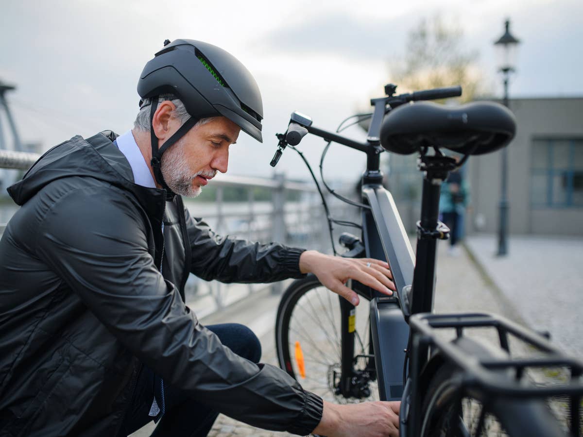 Ein Mann hockt neben einem E-BIke