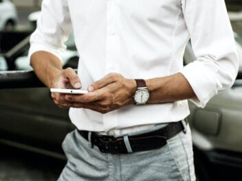 Mann hält ein Smartphone in beiden Händen.