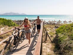 Mann und Frau mit Fahrrad am Strand im Urlaub