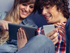 Mann und Frau mit einem Smartphone und einem Tablet