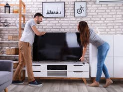 Frau und Mann stellen einen Fernseher auf