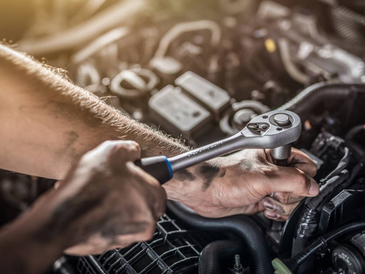 Mechaniker arbeitet im Motorraum eines Autos.