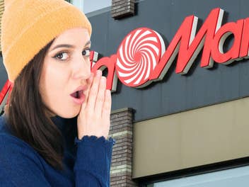 Eine Frau flüstert etwas hinter vorgehaltener Hand, HIntergrund: Ein MediaMarkt ist zu sehen