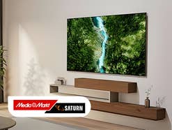 Samsung-Fernseher an der Wand in einem hellen Wohnzimmer. MediaMarkt-Logo drauf.