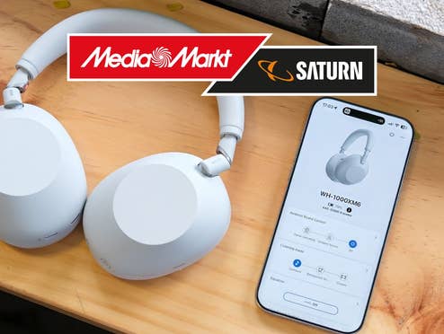 SONY WH-1000XM6 Kopfhörer liegen auf einem Holztisch mit einem Handy daneben.