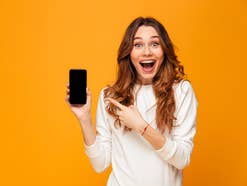 Frau hält überrascht ein Smartphone in der Hand