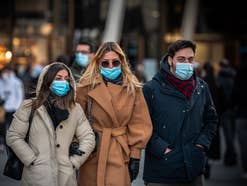 Zwei Frauen und ein Mann mit einer Maske in der Stadt